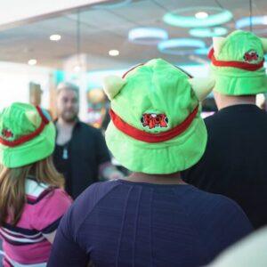 A few Riot Games employees wearing green Riot Games hats at the office