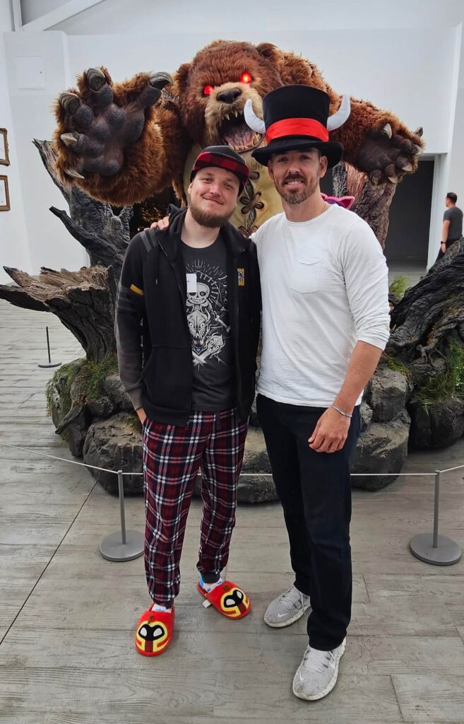 Necrit and Marc Merrill wearing Necrit's iconic YouTube hat in front of Annie and Tibbers